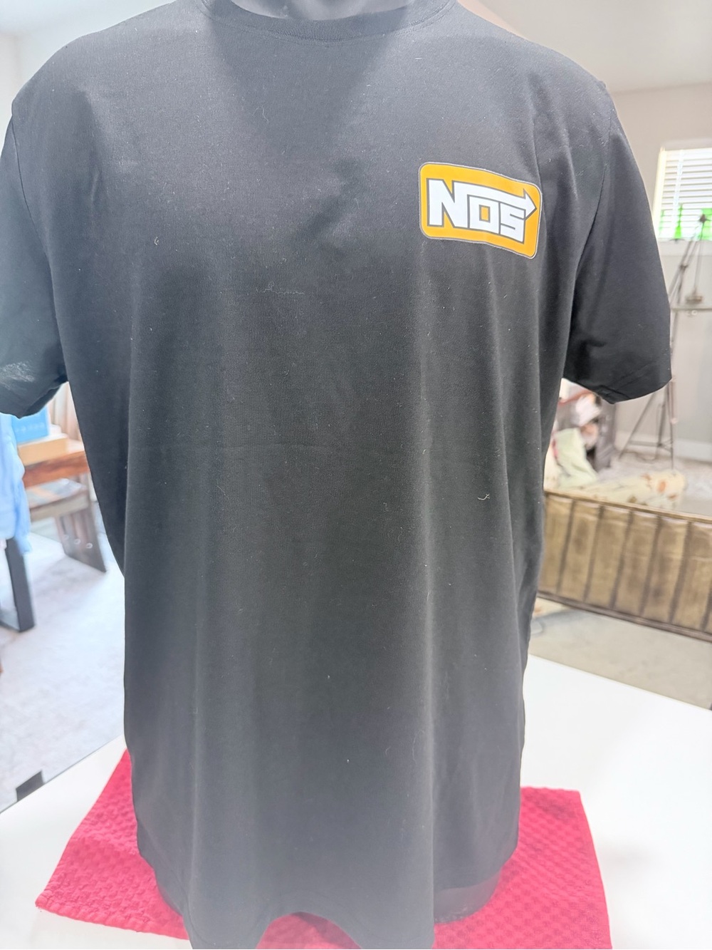 Black crew neck t-shirt emblazoned with the iconic orange and white NOS